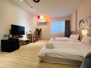 a bedroom with two beds and a flat screen tv at Canal walk inn in Tainan