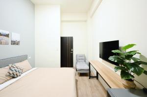a bedroom with a bed and a tv and a chair at 谷園酒店公寓Good Garden Apartment in Taichung