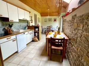 cocina con mesa y pared de piedra en TY AR STIVELL, l’équilibre entre terre et mer 4-7 personnes à MOELAN SUR MER, en Moëlan-sur-Mer