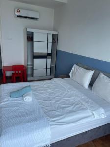 een groot wit bed in een kamer met een rode stoel bij Welcome Home @Reizz Residence in Kuala Lumpur