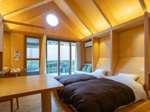 two beds in a room with a table and windows at Kur Park Nagayu in Nitta