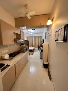 a kitchen with white cabinets and a living room at Good Stay Premium Studio Apartment 206 in Dabolim