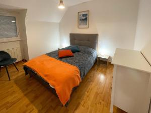 sypialnia z łóżkiem z pomarańczowym kocem w obiekcie Maison BADEN - Golfe du Morbihan w mieście Baden