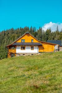 an orange and white barn on a hill in a field at Wellness Chalupa Benešky in Vsetín