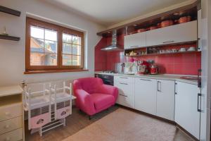 a kitchen with a pink chair in a room at Wellness Chalupa Benešky in Vsetín