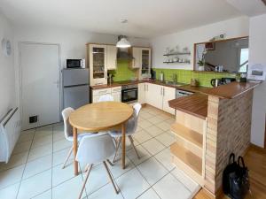 a kitchen with a wooden table and white chairs at Maison BADEN - Golfe du Morbihan in Baden