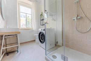 uma casa de banho com uma máquina de lavar roupa e um chuveiro. em Gran.Suite - Central Station em Sankt Pölten