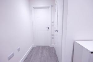 a white hallway with a white door and a wooden floor at Chic City Living - Luxury Apartment in London in Hemel Hempstead