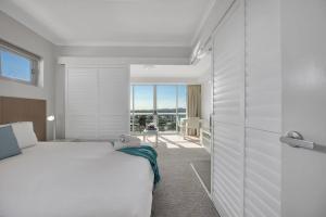 a bedroom with a white bed and a large window at Modern Dual Key Apt w Pool in the heart of Mackay in Mackay
