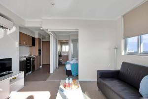 a living room with a black couch and a kitchen at Modern Dual Key Apt w Pool in the heart of Mackay in Mackay