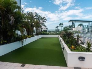 a balcony with green grass and palm trees at Modern Dual Key Apt w Pool in the heart of Mackay in Mackay