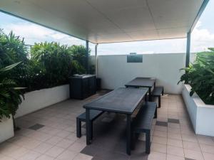 a patio with two tables and benches and plants at Modern Dual Key Apt w Pool in the heart of Mackay in Mackay