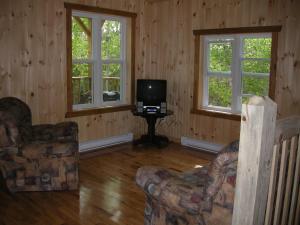 uma sala de estar com duas cadeiras e uma televisão em Chalet des Noisetiers em Tadoussac