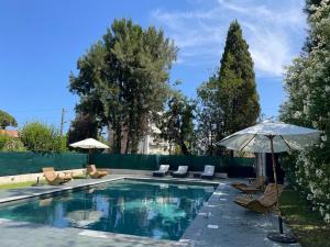 una piscina con sillas y sombrilla en Villa Alexandra Luxury Apartments by Sweet Inn, en Cannes