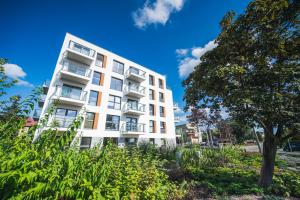 a white building with a tree in front of it at Apartament Baltic Breeze ProstyWynajem Gdańsk Brzeźno in Gdańsk