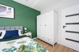 ein Schlafzimmer mit einem Bett und einer grünen Wand in der Unterkunft Apartament Baltic Breeze ProstyWynajem Gdańsk Brzeźno in Danzig