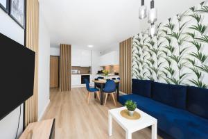 a living room with a blue couch and a table at Apartament Baltic Breeze ProstyWynajem Gdańsk Brzeźno in Gdańsk