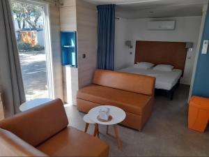une chambre d'hôtel avec un lit, un canapé et une table dans l'établissement Camping Les Jardins d Agathe, au Grau-dʼAgde