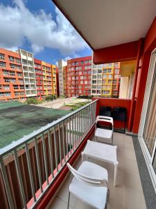 un balcón con sillas, mesas y edificios en Good Stay Studio Apartment 307, en Dabolim