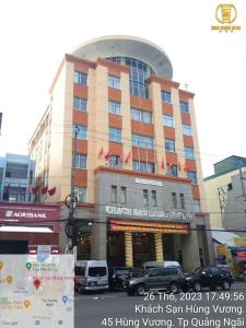 Hung Vuong Hotel في كوانج نجاي: مبنى كبير فيه سيارات تقف امامه