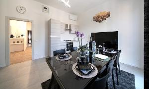 a dining room with a table with chairs and a television at Triumvirato Rooms in Bologna