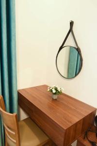 a wooden table with a mirror and a vase of flowers at AnAn Homestay Huế in Hue