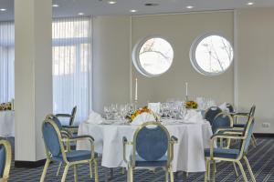 a dining room with a table and chairs and two windows at Sunday Hotel Köln Hürth in Hürth