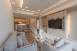 Jasmine Grande Residence في بانكوك: غرفة معيشة مع أريكة بيضاء وتلفزيون