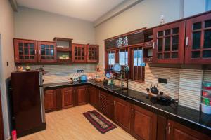 Il comprend une grande cuisine avec des placards en bois et un réfrigérateur. dans l'établissement Lucky cottage, à Habaraduwa Central