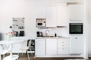 eine weiße Küche mit einer Spüle und einer Mikrowelle in der Unterkunft Peaceful Serviced Apartment Tikkurila, near airport, free parking in Vantaa