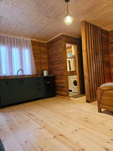 a living room with a kitchen and wooden floors at inSxvava in Ambrolauri