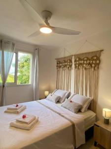 1 dormitorio con 1 cama blanca grande y toallas. en Villa Albizia 974 avec piscine et spa, en Saint-Pierre