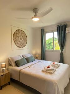 Schlafzimmer mit einem großen weißen Bett und einem Fenster in der Unterkunft Villa Albizia 974 avec piscine et spa in Saint-Pierre