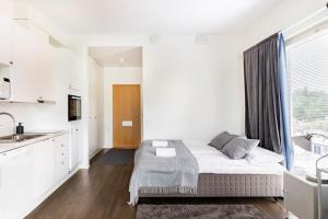 ein weißes Schlafzimmer mit einem Bett und einer Küche in der Unterkunft Peaceful Serviced Apartment Tikkurila, near airport, free parking in Vantaa