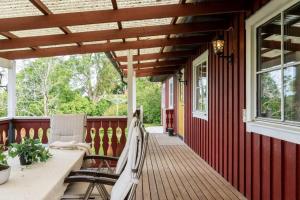 een veranda van een rood huis met een tafel en stoelen bij A countryside villa close to Uppsala! in Uppsala