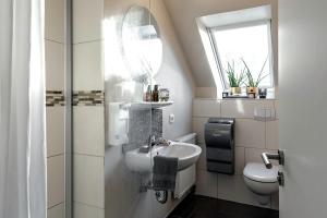 a bathroom with a sink and a toilet and a mirror at Pension Haus am Kohfurth in Norderstedt +47 photos