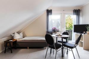 een slaapkamer met een bed en een tafel en stoelen bij Pension Haus am Kohfurth in Norderstedt