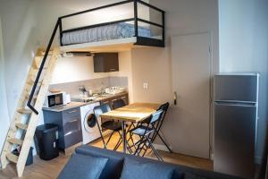 a small kitchen with a table and a loft bed at L'Althéa II in Bron