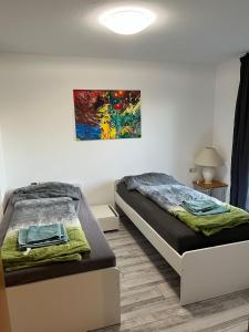 twee bedden in een kamer met een schilderij aan de muur bij Dimai House No 17 Dornbirn Zentrum in Dornbirn
