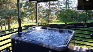 een hot tub op een terras met uitzicht op de bomen bij Czarna Chata II Luxury Resort in Ropa
