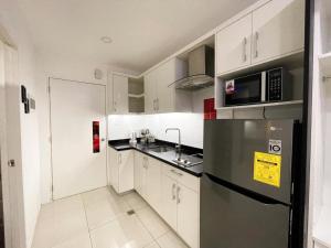 La cuisine est équipée de placards blancs et d'un réfrigérateur noir. dans l'établissement Kandi Palace Hotel D20, à Ángeles