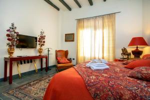 una camera da letto con un letto, una scrivania e una televisione di Borgo Antico XIX sec. a Gesturi