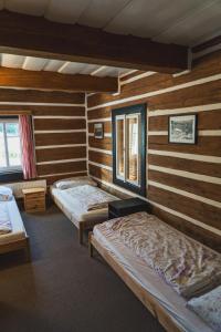 two beds in a room with wooden walls at Bouda Matouš - Friesovy boudy in Strážné