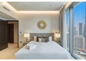 een slaapkamer met een groot wit bed en een groot raam bij bnbmehomes - Breathtaking Downtown Views at BLVD - 3801 in Dubai
