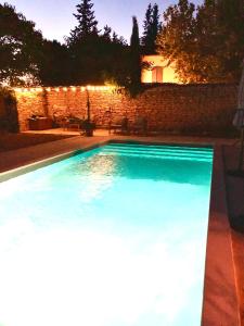 uma piscina num quintal à noite com luzes em Le Mas Justin em Gordes