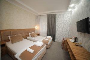 una camera d'albergo con due letti e una televisione di Hotel Tinchlik Plaza a Urganch