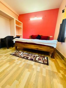 uma cama num quarto com uma parede vermelha em Mangalam guest house em Puri