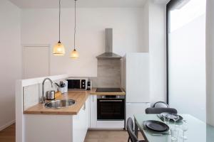 Una cocina blanca con un fregadero y una mesa. en Luxury apartment Alfortville, en Alfortville