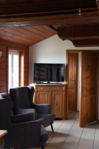 a living room with two chairs and a flat screen tv at Bouda Matouš - Friesovy boudy in Strážné