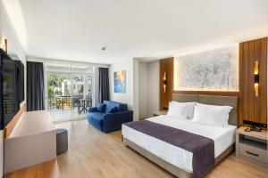 Habitación de hotel con cama y silla azul en Simena Comfort Hotel en Kemer